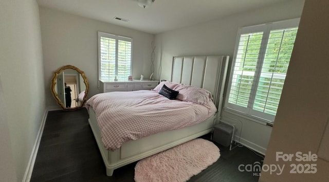 bedroom with baseboards, multiple windows, and wood finished floors