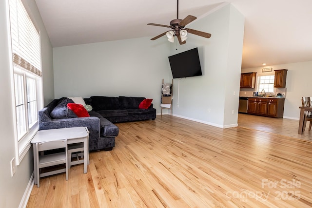 living room featuring light wood-type flooring, vaulted ceiling, baseboards, and ceiling fan