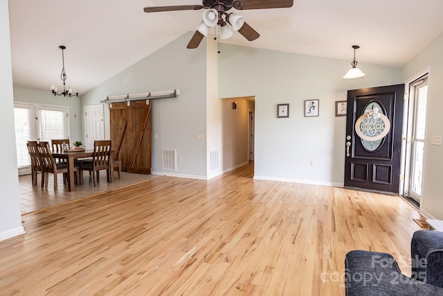 dining room with ceiling fan, a barn door, light wood-style flooring, and visible vents