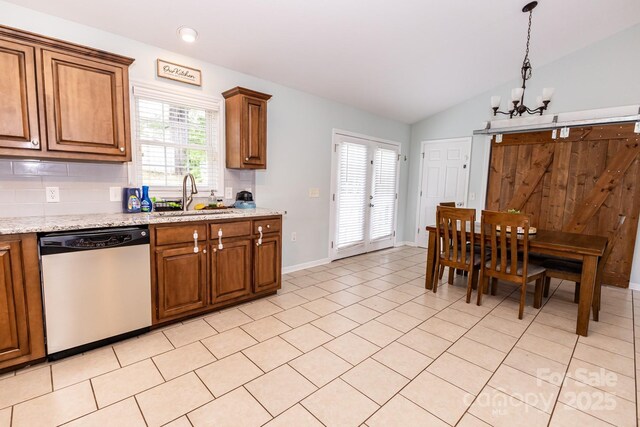kitchen featuring dishwasher, brown cabinetry, baseboards, a sink, and a chandelier