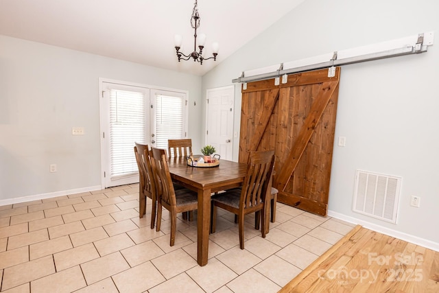 dining room featuring a notable chandelier, a barn door, baseboards, visible vents, and vaulted ceiling
