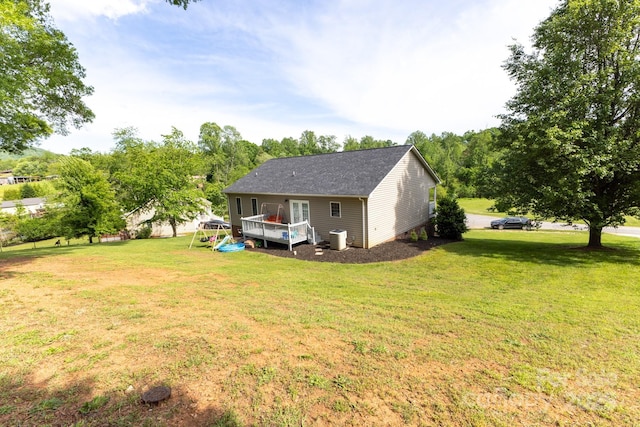 rear view of house with a lawn, cooling unit, and a wooden deck