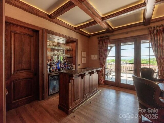 bar with beverage cooler, coffered ceiling, beam ceiling, a community bar, and dark wood-style floors