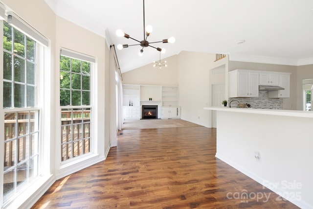 1465 Porters Ct, Concord, NC 28025 - unfurnished living room with a chandelier, dark wood finished floors, ornamental molding, vaulted ceiling, and a glass covered fireplace