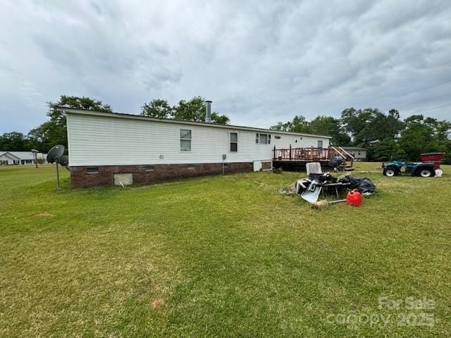 rear view of property featuring crawl space, a deck, and a lawn