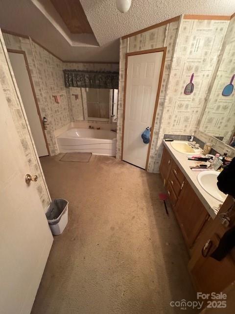 bathroom featuring double vanity, wallpapered walls, a textured ceiling, and a bath