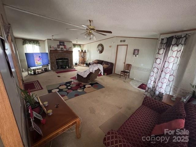 living room with a ceiling fan, a textured ceiling, carpet, visible vents, and a brick fireplace