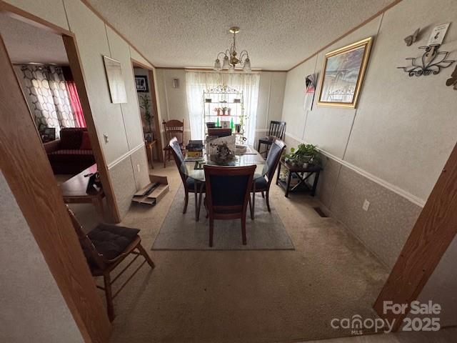 dining space featuring an inviting chandelier, plenty of natural light, carpet, and a textured ceiling