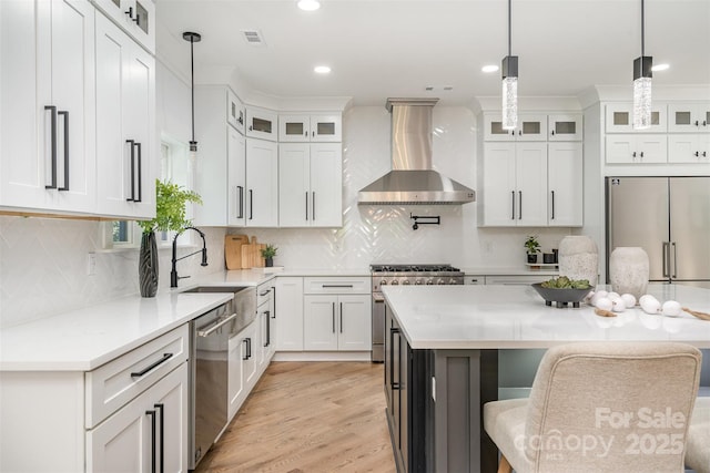 2224 Highland St, Charlotte, NC 28208 - kitchen featuring wall chimney exhaust hood, premium appliances, a sink, a breakfast bar, and light countertops