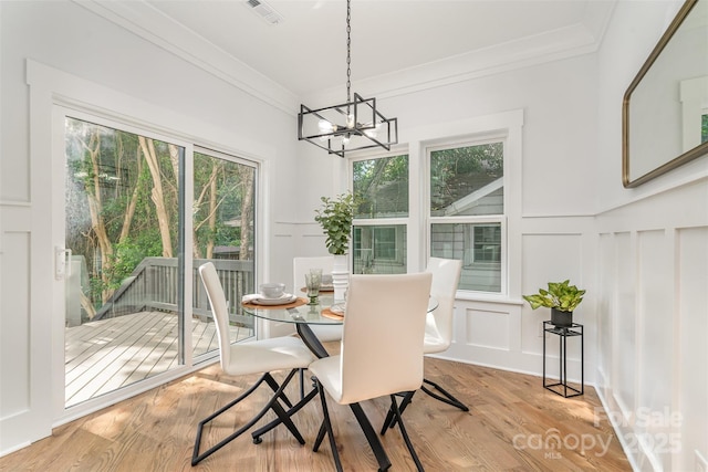 2224 Highland St, Charlotte, NC 28208 - dining space featuring a decorative wall, light wood-style flooring, ornamental molding, a chandelier, and wainscoting