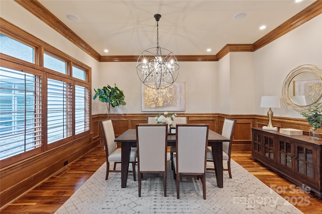 dining room with wood finished floors, a chandelier, crown molding, a wainscoted wall, and recessed lighting