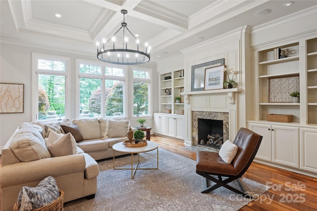 living room featuring healthy amount of natural light, a chandelier, ornamental molding, wood finished floors, and beam ceiling