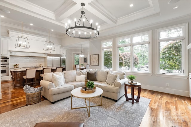 living area featuring a chandelier, light wood-style floors, crown molding, beamed ceiling, and baseboards