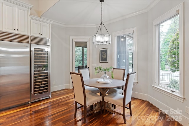 dining area with plenty of natural light, wood finished floors, baseboards, and crown molding