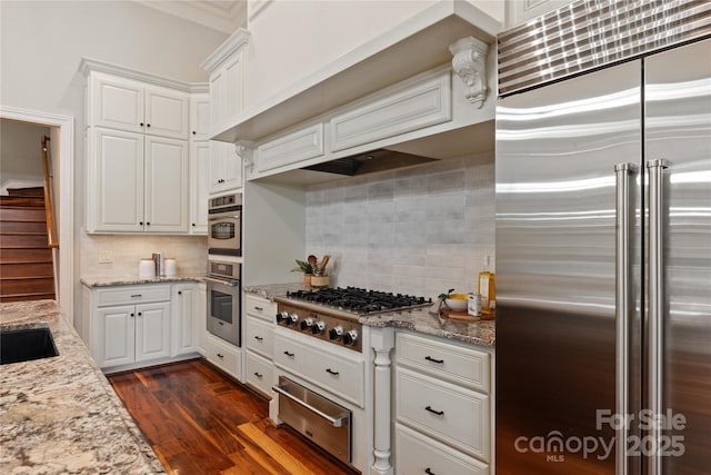 kitchen featuring appliances with stainless steel finishes, a warming drawer, decorative backsplash, and white cabinetry