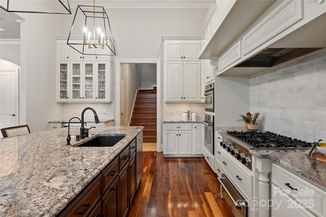 kitchen with a sink, appliances with stainless steel finishes, white cabinets, dark brown cabinets, and decorative backsplash