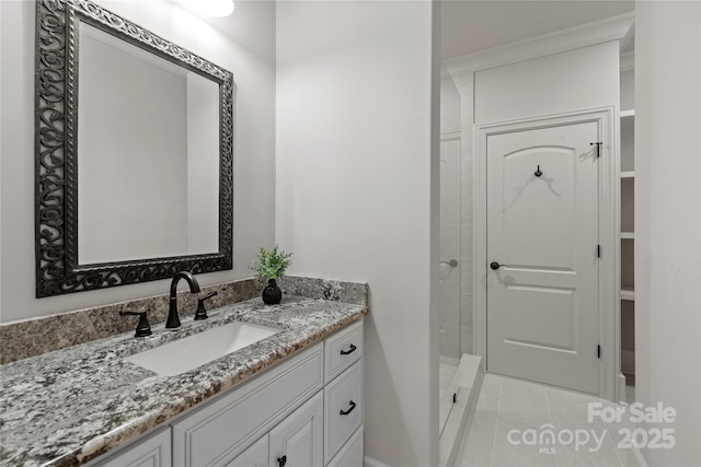 bathroom featuring marble finish flooring, baseboards, vanity, a tile shower, and ornamental molding