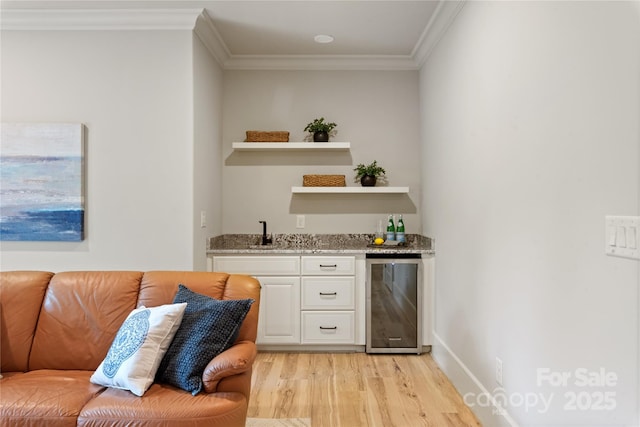 indoor wet bar featuring wine cooler, light wood finished floors, and ornamental molding