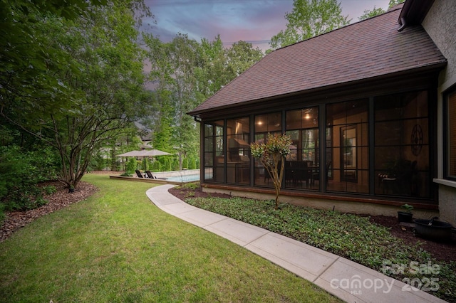view of grassy yard with a sunroom and a pool