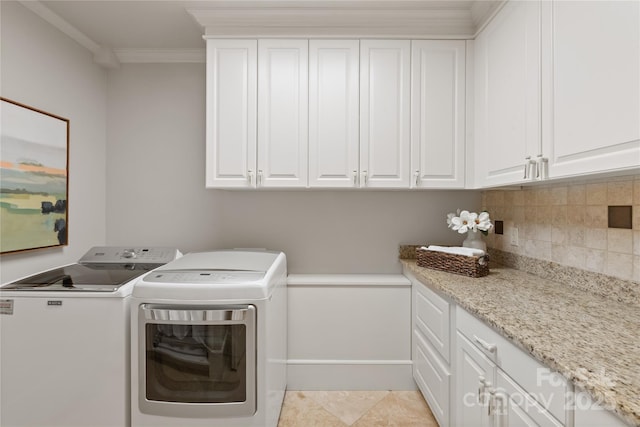 laundry area with washing machine and dryer, cabinet space, crown molding, and baseboards