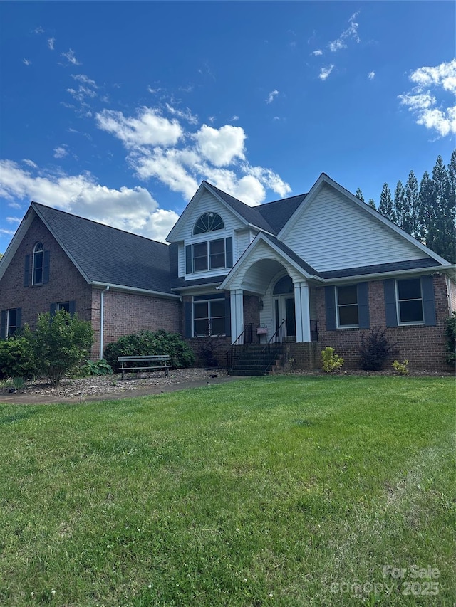 view of front of home with brick siding, a porch, and a front lawn