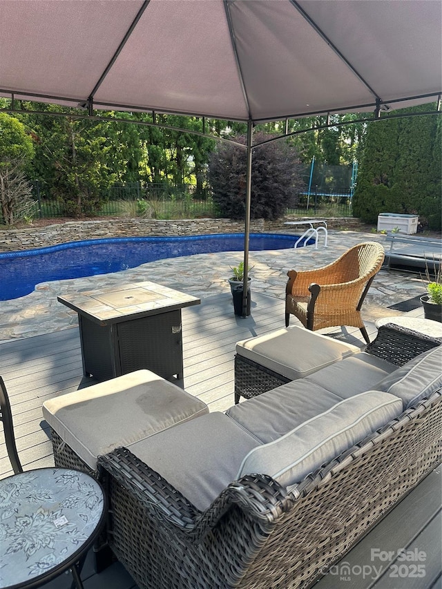 view of patio with a trampoline, a wooden deck, and an outdoor hangout area