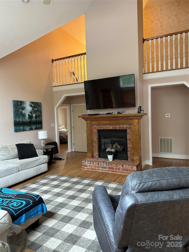 living room with high vaulted ceiling, wood finished floors, and a fireplace