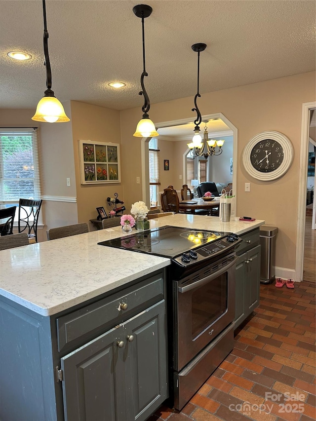 kitchen featuring electric range, gray cabinetry, a textured ceiling, open floor plan, and a chandelier