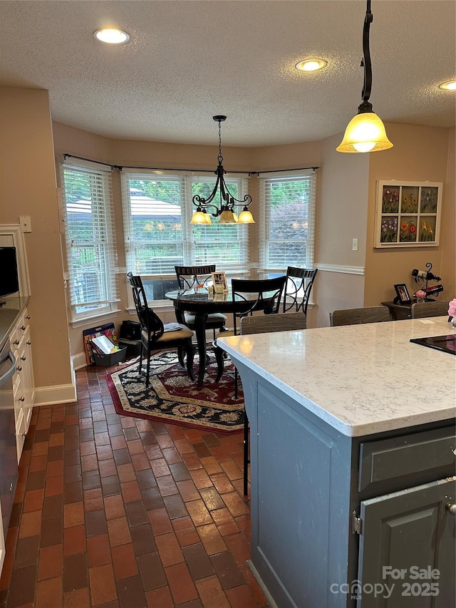 kitchen featuring a textured ceiling, pendant lighting, recessed lighting, a chandelier, and a breakfast bar