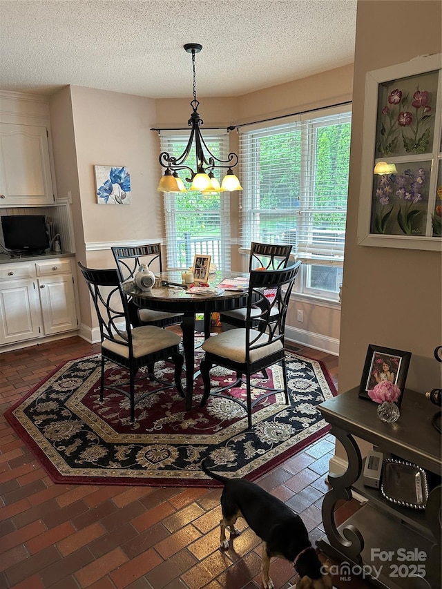 dining area with a chandelier, a textured ceiling, and baseboards