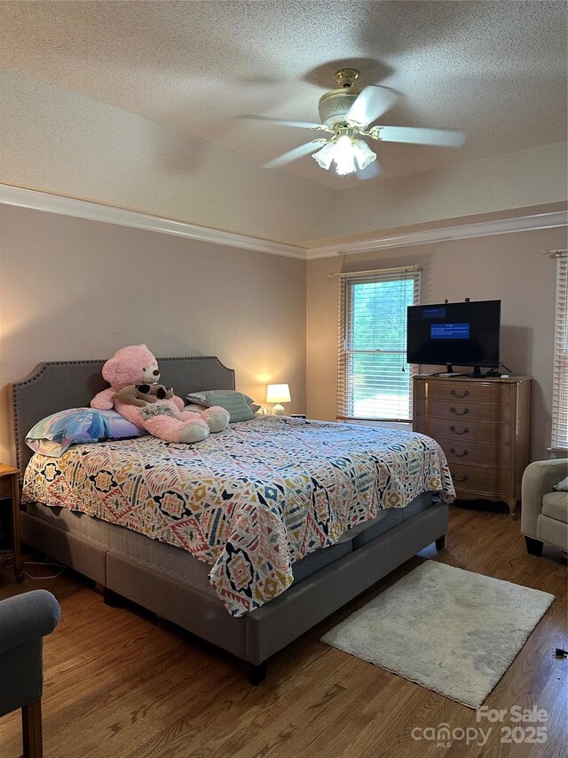 bedroom featuring wood finished floors, ornamental molding, a textured ceiling, and a ceiling fan