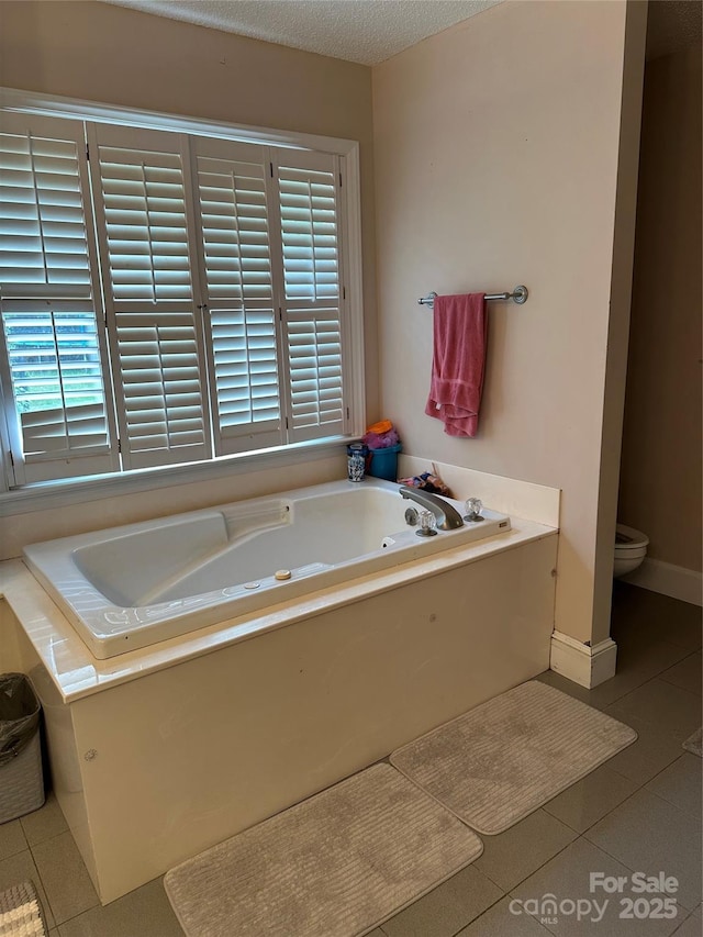 full bath featuring tile patterned floors, a garden tub, and toilet
