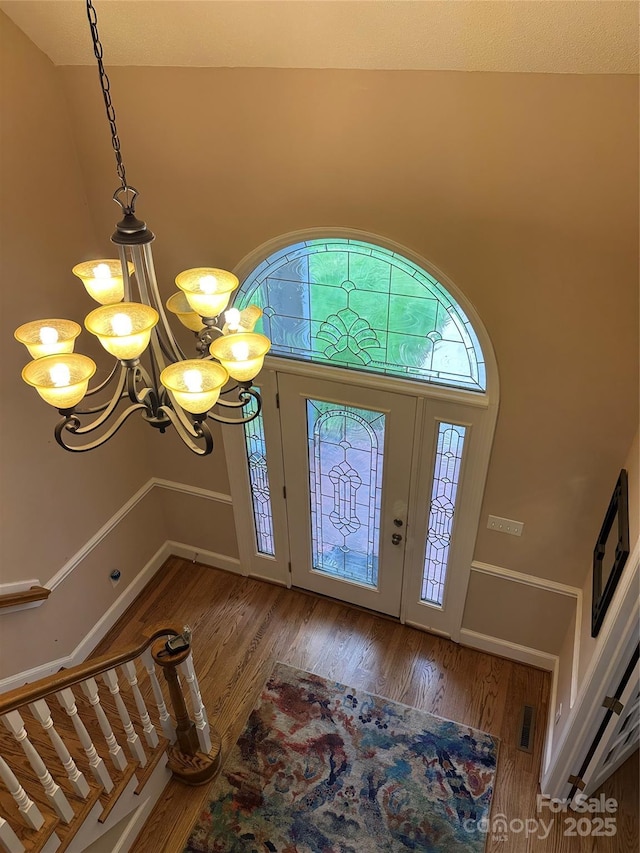 entrance foyer with wood finished floors, a chandelier, and a towering ceiling