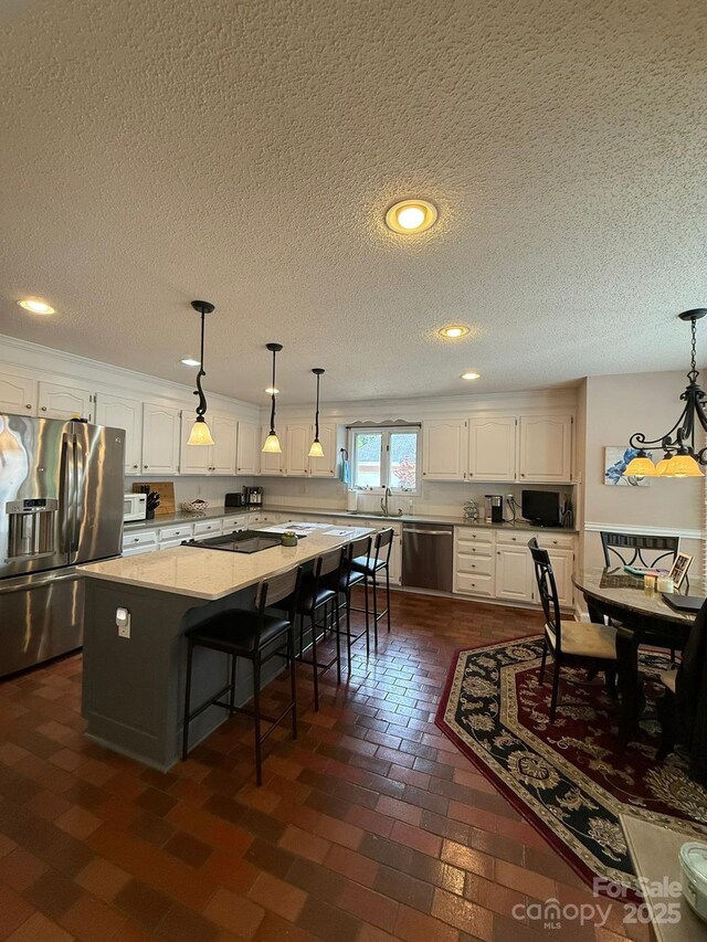 504 Johnsfield Rd, Shelby, NC 28150 - kitchen featuring appliances with stainless steel finishes, white cabinetry, a center island, a textured ceiling, and decorative light fixtures