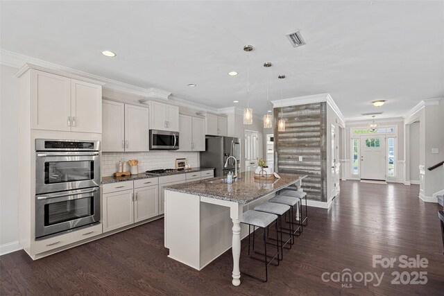 10906 Charmont Pl, Huntersville, NC 28078 - kitchen featuring appliances with stainless steel finishes, a breakfast bar, an island with sink, dark wood finished floors, and ornamental molding