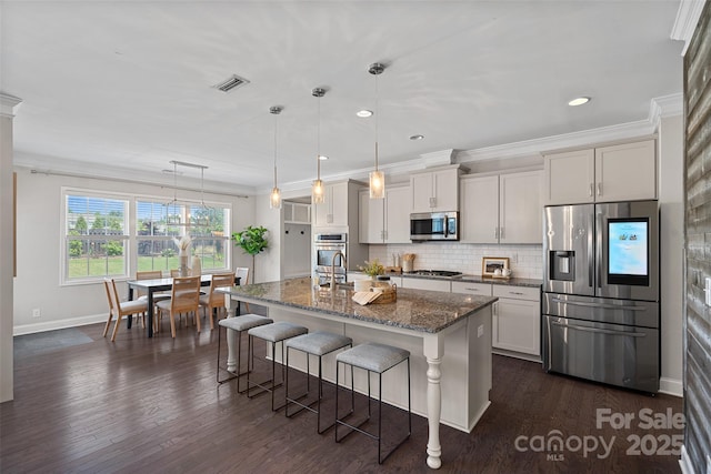 10906 Charmont Pl, Huntersville, NC 28078 - kitchen featuring stainless steel appliances, a breakfast bar area, a center island with sink, baseboards, and dark stone counters