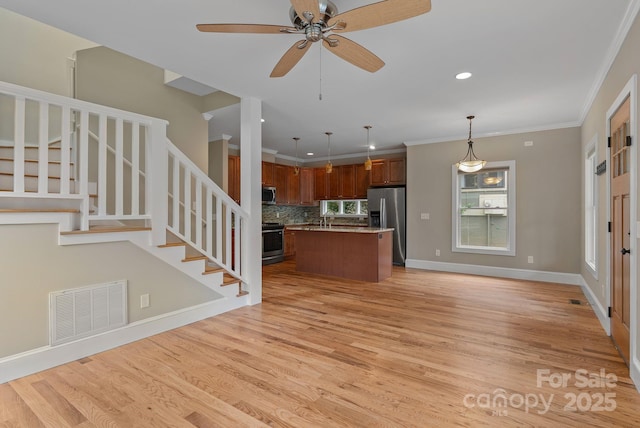 38 Unadilla Aly, Asheville, NC 28803 - kitchen featuring appliances with stainless steel finishes, open floor plan, an island with sink, light wood-style floors, and tasteful backsplash