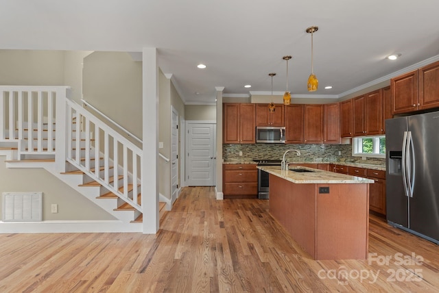 38 Unadilla Aly, Asheville, NC 28803 - kitchen with appliances with stainless steel finishes, crown molding, tasteful backsplash, light wood-style flooring, and a kitchen island with sink