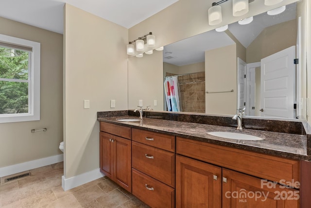 38 Unadilla Aly, Asheville, NC 28803 - bathroom with baseboards, double vanity, tiled shower, and toilet