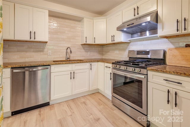 9 N St, Weaverville, NC 28787 - kitchen with under cabinet range hood, stainless steel appliances, a sink, white cabinets, and tasteful backsplash