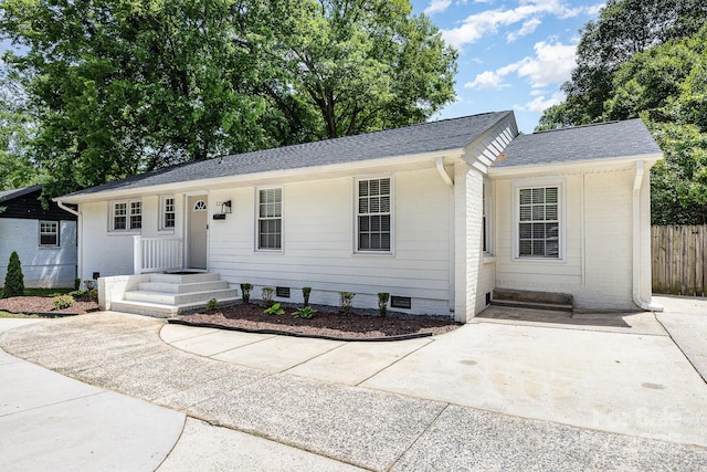 ranch-style home featuring fence and roof with shingles