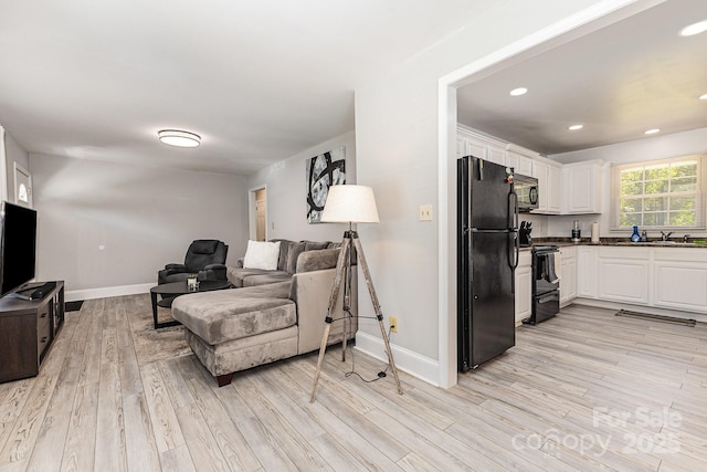 living area with light wood-style flooring, baseboards, and recessed lighting