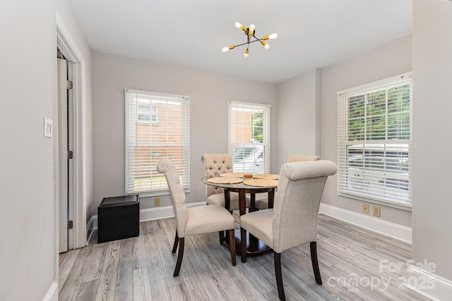 dining space featuring a chandelier, healthy amount of natural light, light wood finished floors, and baseboards