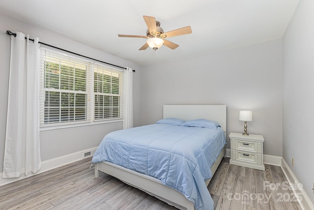 bedroom with light wood-style floors, baseboards, and a ceiling fan