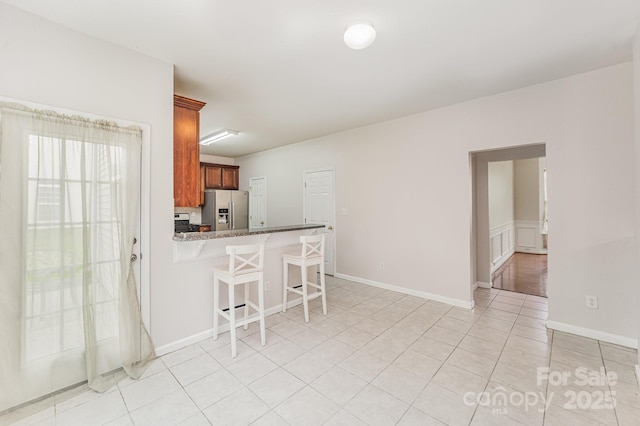 15037 Taylor Ridge Ln Unit 25, Charlotte, NC 28273 - kitchen with stainless steel fridge, a breakfast bar, light tile patterned floors, brown cabinets, and a peninsula