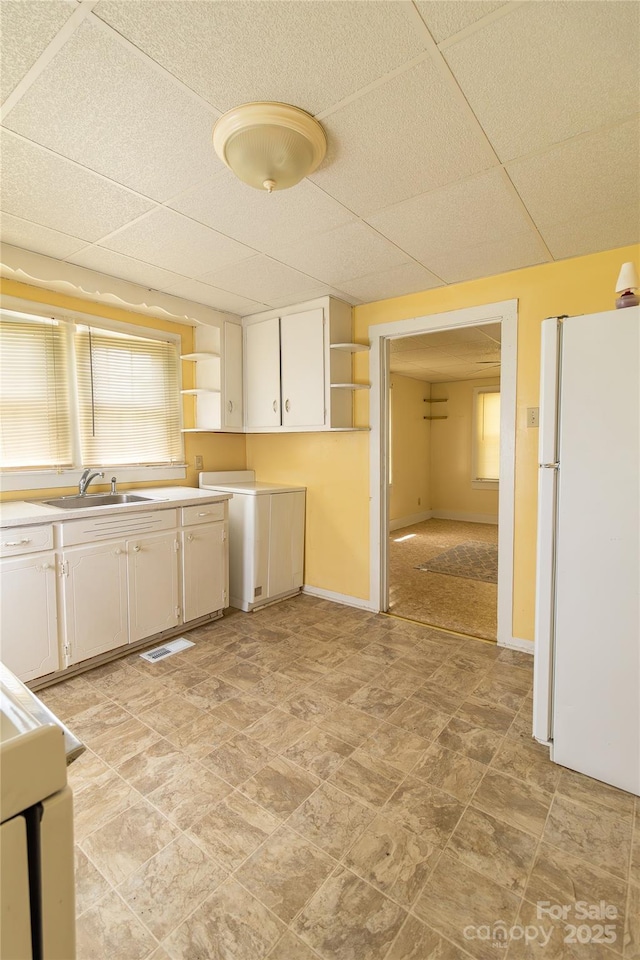 kitchen featuring freestanding refrigerator, a paneled ceiling, open shelves, and a sink