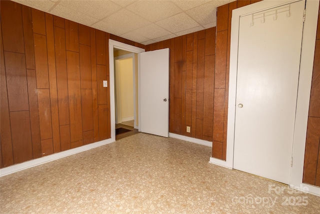 spare room featuring wood walls and a paneled ceiling