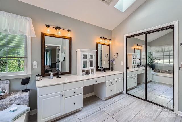 7600 Ridgefield Dr, Charlotte, NC 28269 - bathroom with a sink, double vanity, plenty of natural light, and vaulted ceiling with skylight