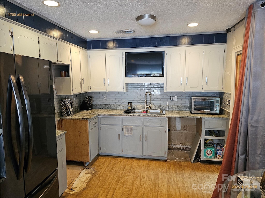 1700 Old Towne Ct, Charlotte, NC 28217 - kitchen with freestanding refrigerator, a sink, a textured ceiling, light wood-style flooring, and white cabinetry