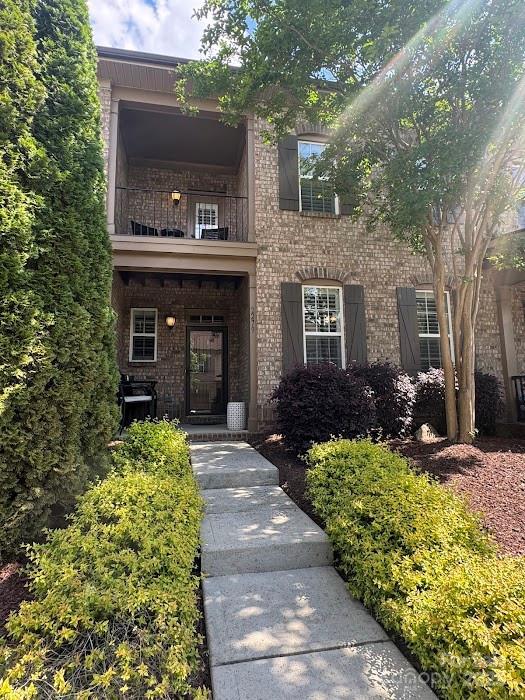 view of front of home with a balcony and brick siding
